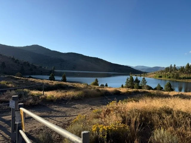 The lake from the entrance gate — sagebrush and dry grass in the foreground, the water beyond.