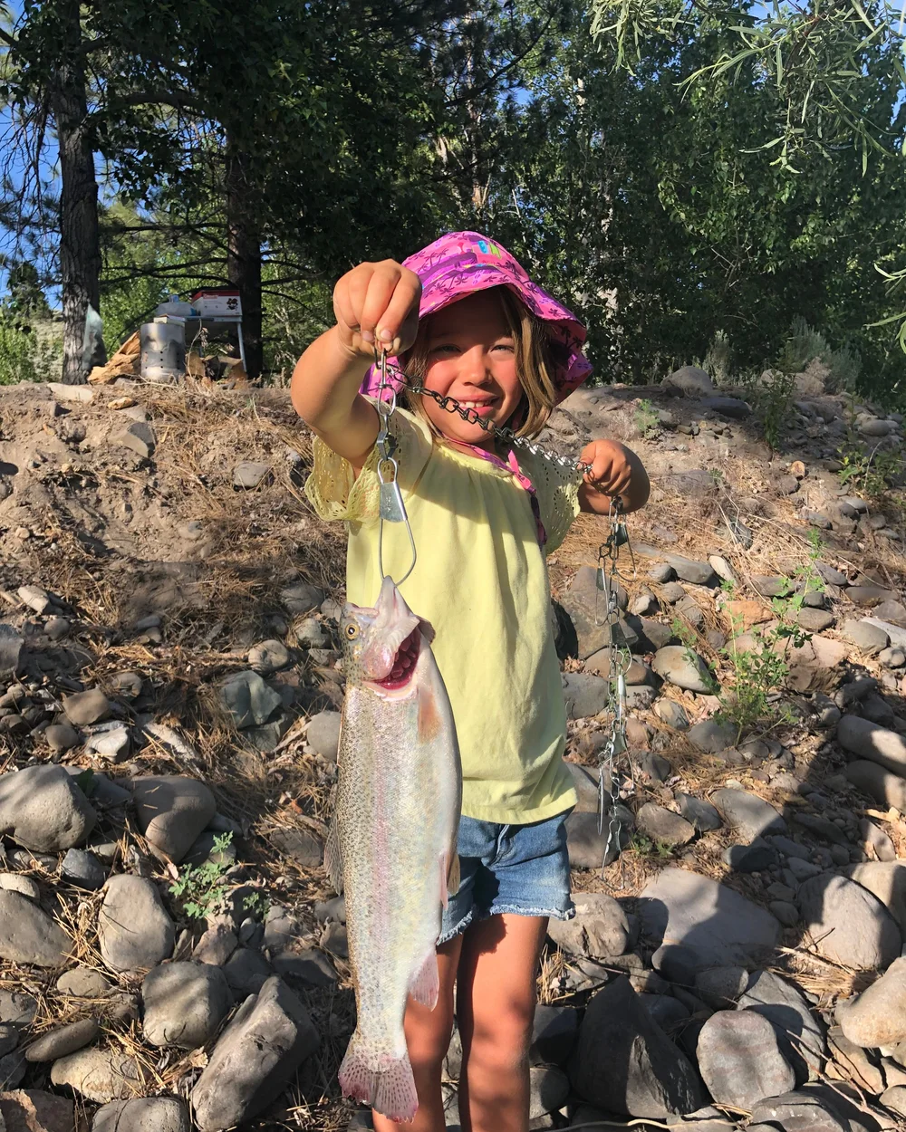 A young angler on the resort bank holding up a rainbow trout caught in the East Fork out front.