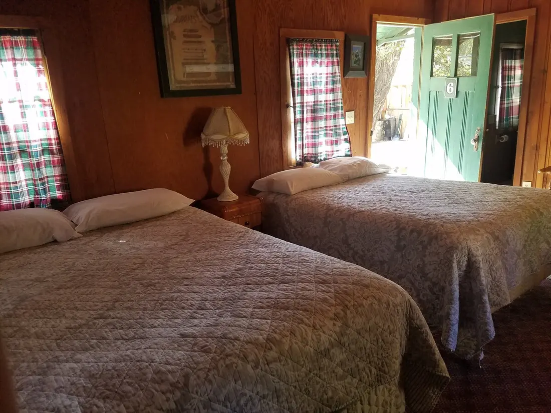 The bedroom — Two beds with the green door open beside them, light coming in from the porch.