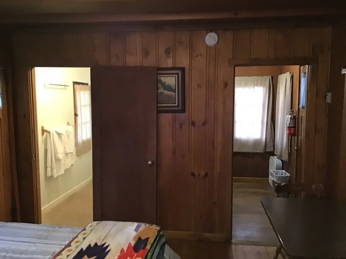 The bedroom — Looking through the cabin — the bathroom door open on one side, a second doorway on the other, the bed in the foreground.