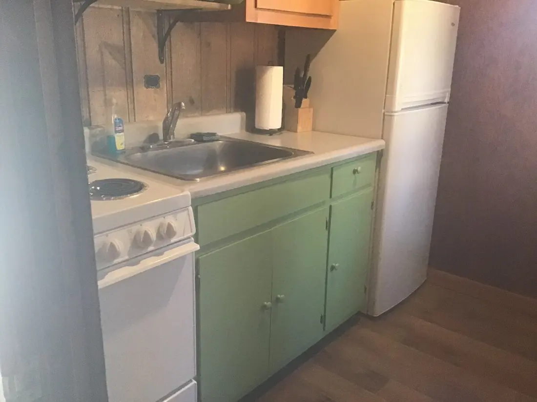 The kitchen — electric range, stainless sink, mint-green cabinets and a full-size refrigerator.