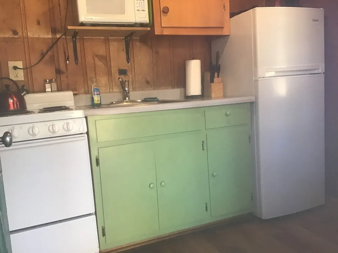 The kitchen wall — microwave above the counter, range and sink, knife block and paper towel at hand.