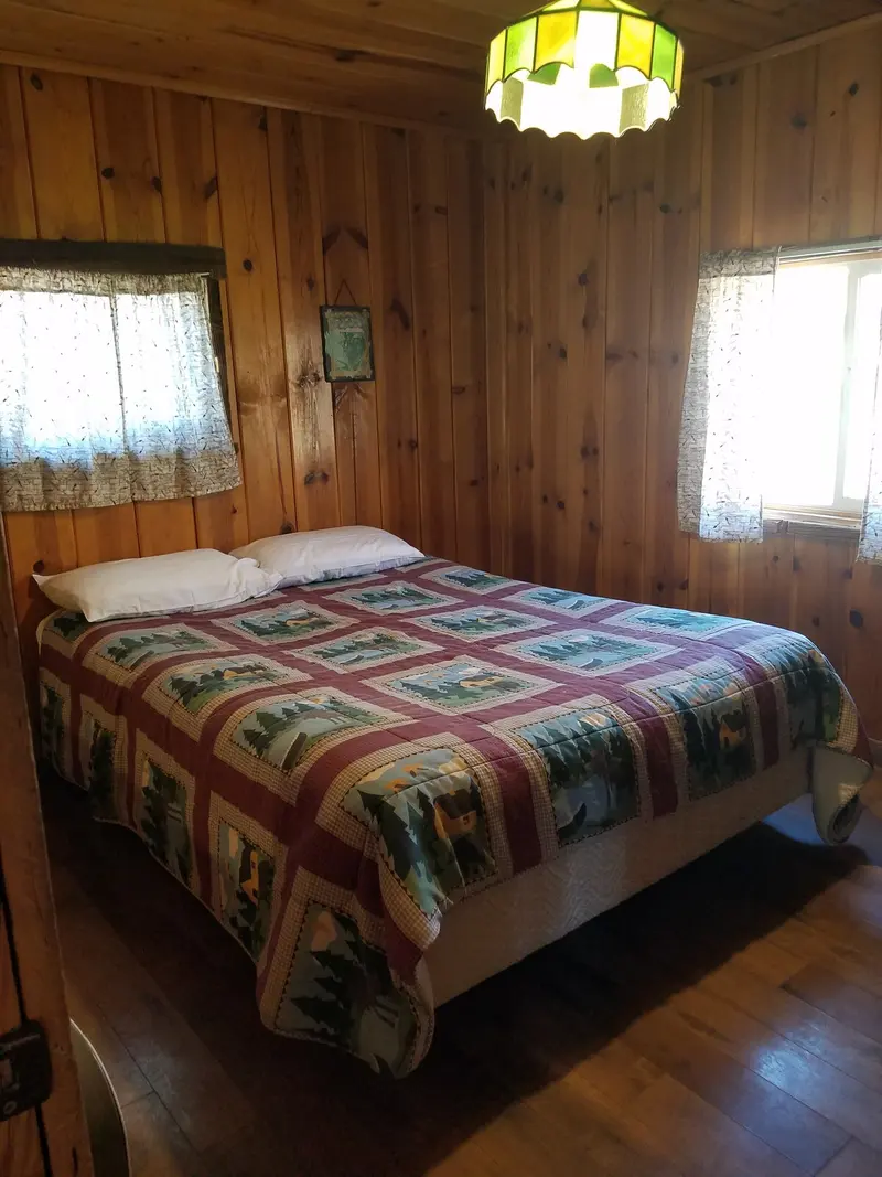 The beds — Another bed beneath a stained-glass ceiling lamp, a window to either side.