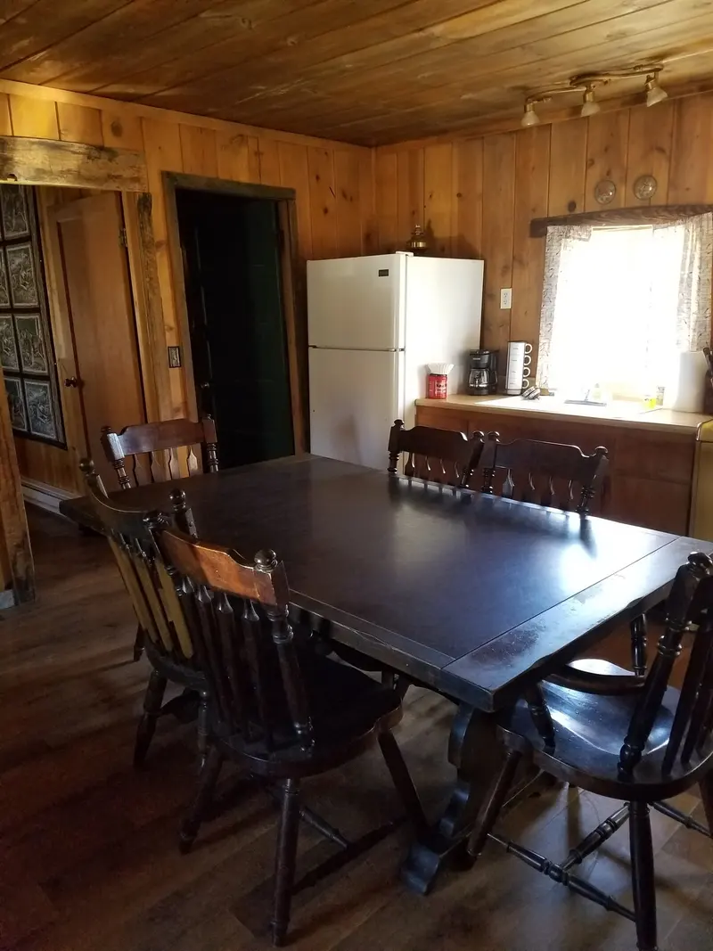 The dining room — The dining table from the corner, chairs pulled in, the kitchen behind it.