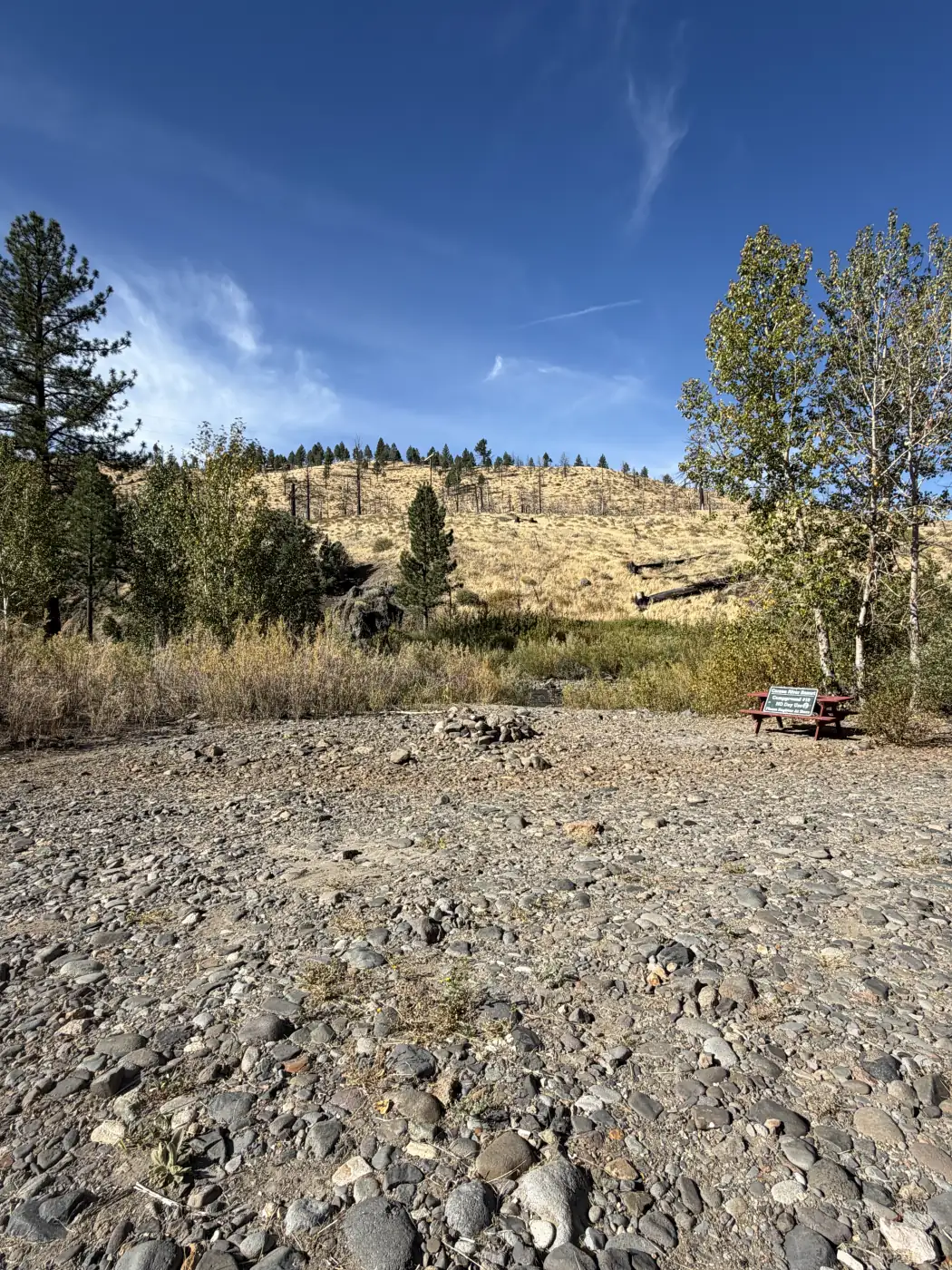 Riverside site 10 — the table on the bar with the hillside behind, up the highway before the resort — the owner's photograph, September 2026.