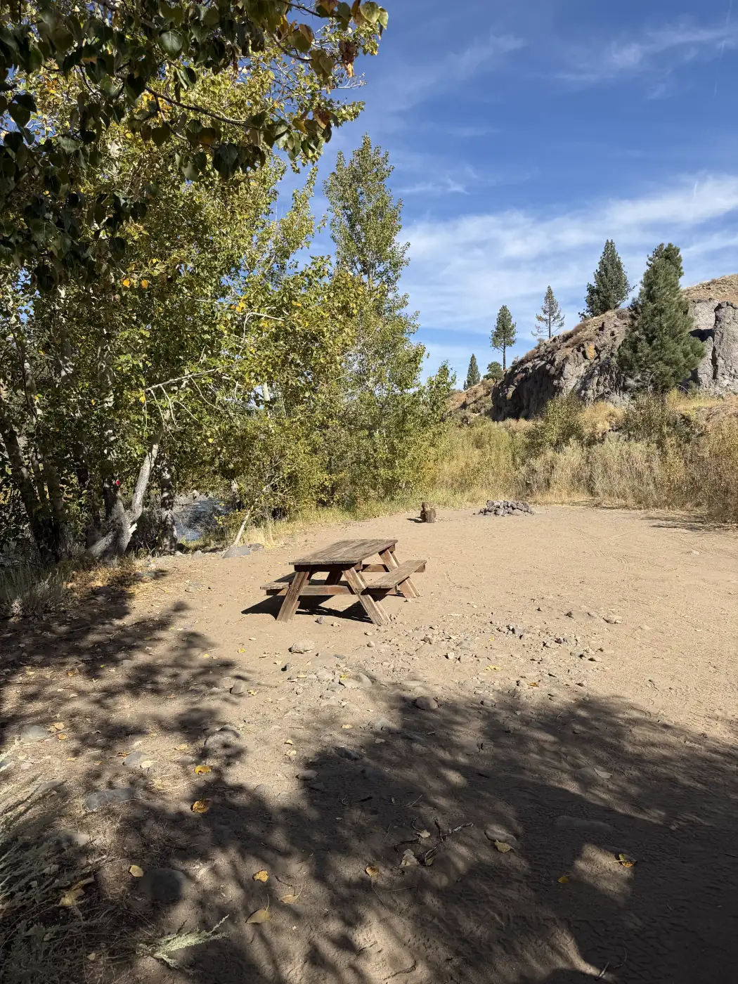 A table on the gravel between sites 7 and 9, the rocks and the trees — the owner's photograph, September 2026.