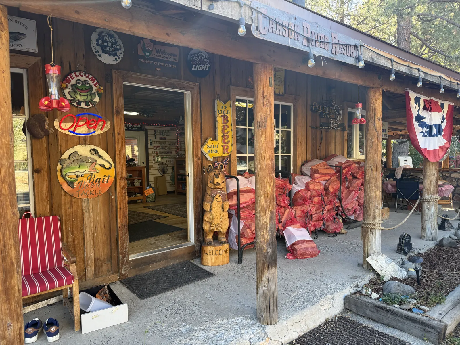 The front door — the OPEN sign, the carved bear, and the winter's firewood.