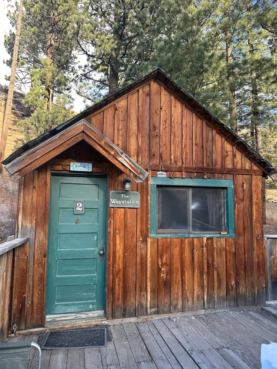 The Waystation — cabin №2, the green door and its name board, under the pines.